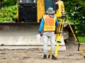 Geodeta w kamizelce odblaskowej z niwelatorem i dokumentami. Zastanawiasz się, ile zarabia geodeta po technikum?