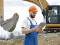 Operator koparki z tabletem w ręku, analizuje dane. Zastanawia się, ile zarabia koparkowy, planując swoją karierę.
