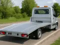 Srebrna autolaweta z pomarańczowymi światłami ostrzegawczymi, gotowa do transportu. Wynajem autolawety kat C.
