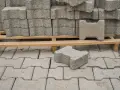 Stos kostki brukowej na palecie. Widać pojedyncze elementy, które posłużą do ułożenia nawierzchni. Zastanawiasz się, ile grysu pod kostkę potrzebujesz?