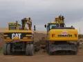 Dwie żółte koparko-ładowarki, CAT i Komatsu, stoją na placu budowy. Czy koparko ładowarka musi być zarejestrowana?