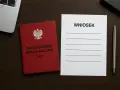 Czerwona książeczka z orłem i napisem "Zaświadczenie Kwalifikacyjne UDT" obok formularza "Wniosek" i długopisu. Przygotowanie do złożenia wniosku o przedłużenie uprawnień UDT online.