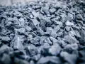 Głęboki, szary żwir do betonu, ułożony w dużą hałdę. Kamienie są ostre i nieregularne, tworząc teksturę idealną do budowy.