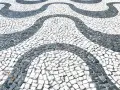 Fale o preço do kamień pod kostkę, który tworzy falisty wzór na chodniku z czarno-białych kamieni.
