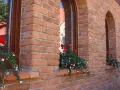 Elegancka elewacja z cegły klinkierowej, z kwitnącymi pelargoniami przy oknach. Sprawdź, jaka jest cegła klinkierowa cena!