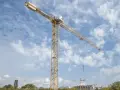 Żółty dźwig budowlany na tle błękitnego nieba z chmurami. Zastanawiasz się, ile zarabia operator dźwigu?