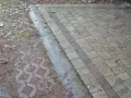 Podbudowa pod kostkę brukową na glinie, z widocznym wzorem ażurowym i kamieniami.
