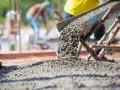 Betoniarka wysypuje świeży beton na plac budowy. Ile betoniarek na 1m3 betonu? To zależy od wielkości betoniarki i jej wydajności.
