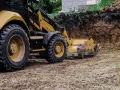 Koparka pracuje nad tym, jak wyrównać działkę, usuwając ziemię z wykopu.