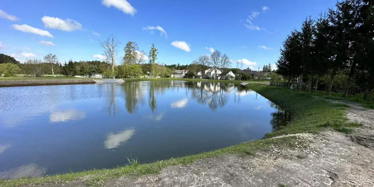 Piękny, świeżo wykopany staw. Zastanawiasz się, ile kosztuje wykopanie stawu? Warto zainwestować w taki krajobraz.