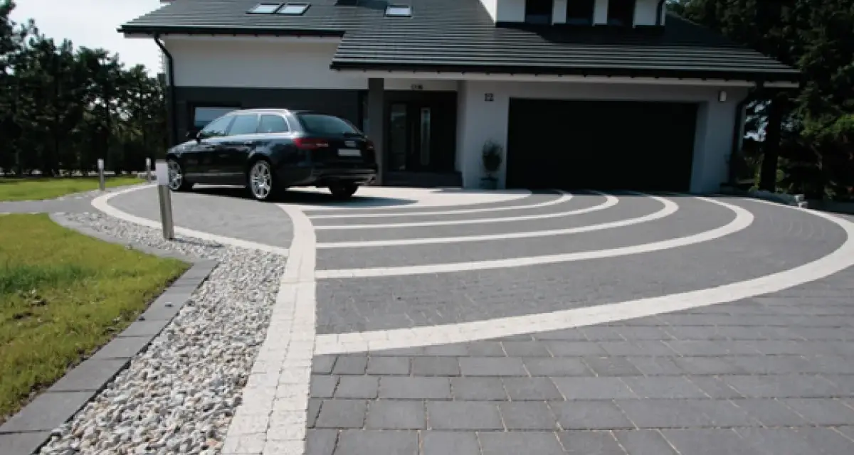 Nowoczesny podjazd z kostki brukowej, gdzie suchy beton pod kostkę tworzy idealne podłoże dla eleganckiego wzoru.