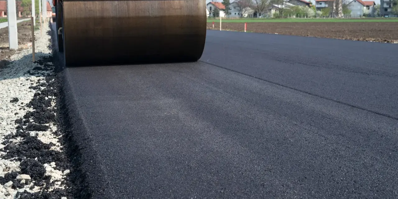 Walec drogowy ugniata świeży asfalt. Zastanawiasz się, ile kosztuje 100 m asfaltu na drodze dojazdowej do domu?
