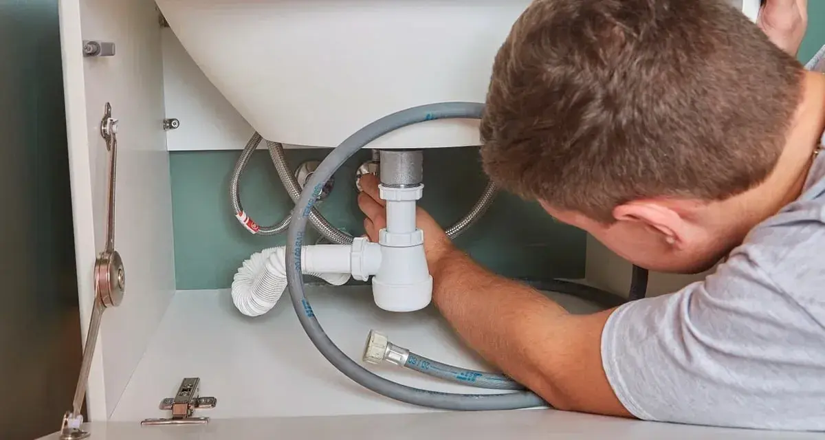 Hydraulik naprawia syfon pod zlewem. Zastanawiasz się, ile kosztuje hydraulik?