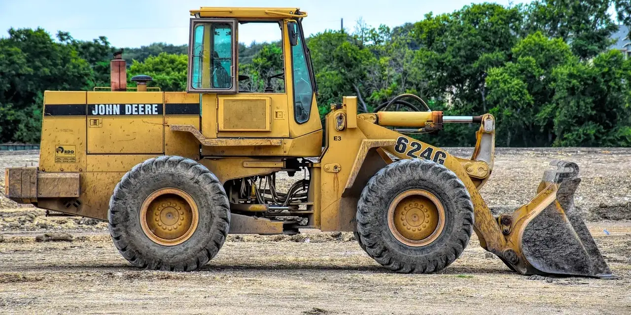 Żółta koparko-ładowarka John Deere 624G gotowa do pracy, wymaga odpowiednich uprawnień do obsługi.