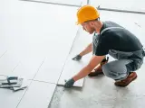 Fachowiec układa płytki na balkonie. Dowiedz się, ile kosztuje położenie płytek na balkonie i jakie materiały są potrzebne.