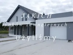 Nowoczesny dom z szarą elewacją i białym garażem. Tynk zewnętrzny typu baranek nadaje mu unikalny charakter.