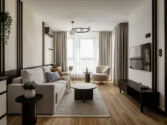Nowoczesny salon z beżową kanapą, fotelem i telewizorem.