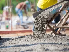 Betoniarka wysypuje świeży beton na plac budowy. Ile betoniarek na 1m3 betonu? To zależy od wielkości betoniarki i jej wydajności.