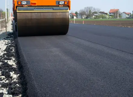 Walec drogowy ubija świeży asfalt. Zastanawiasz się, ile kosztuje położenie asfaltu prywatnie?