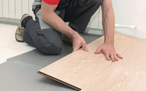 Ręce układają jasny duripanel na szarej podkładce.