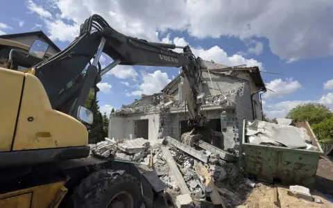 Koparka Volvo niszczy budynek. Trwa rozbiórka budynku, cena za m2 jest kluczowa przy planowaniu prac.