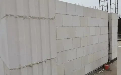Ściana z bloczków silikatowych wznoszona na budowie. Widać zbrojenie i fragmenty fundamentów.