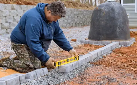 Budowniczy sprawdza poziom kostki brukowej, by zapewnić idealny spadek na kostce brukowej. Obok stoi nietypowy, czarny obiekt.