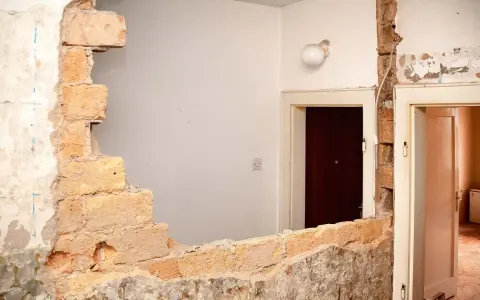 Rozbiórka budynku, odsłonięta wspólna ściana z cegieł między drzwiami.