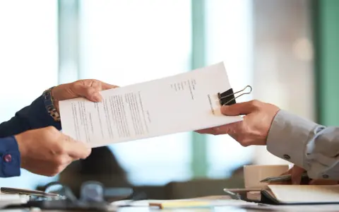 Dwie osoby przekazują sobie dokument "PARTNERSHIP AGREEMENT". To ważny moment, być może ustalanie co to dtr w umowie.