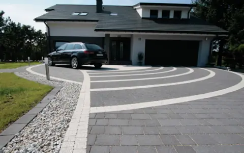 Nowoczesny podjazd z kostki brukowej, gdzie suchy beton pod kostkę tworzy idealne podłoże dla eleganckiego wzoru.