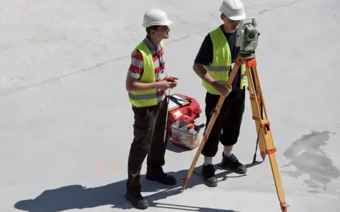Dwóch geodetów pracuje na budowie. Zastanawiasz się, ile zarabia geodeta w Niemczech?