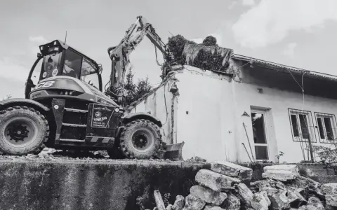 Koparka rozbiórkowa pracuje przy budynku. Wniosek o pozwolenie na rozbiórkę wzór wypełniony, dokumentacja prac rozbiórkowych.