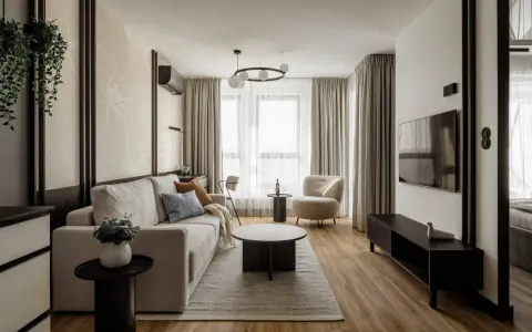 Nowoczesny salon z beżową kanapą, fotelem i telewizorem.
