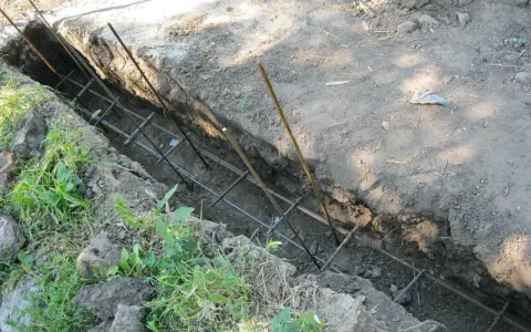 Wykonanie fundamentu pod ogrodzenie. W wykopie widoczna zbrojenie z prętów stalowych, gotowe do zalania betonem.