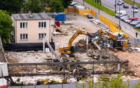 Dwie koparki pracują przy rozbiórce budynku. To przykład zgłoszenia rozbiórki budynku, gdzie widać postęp prac.