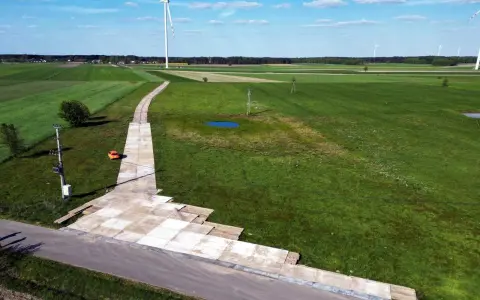 Teren budowy farmy wiatrowej z tymczasową drogą z płyt betonowych. Tłuczeń na drodze ułatwia dojazd ciężkiego sprzętu.
