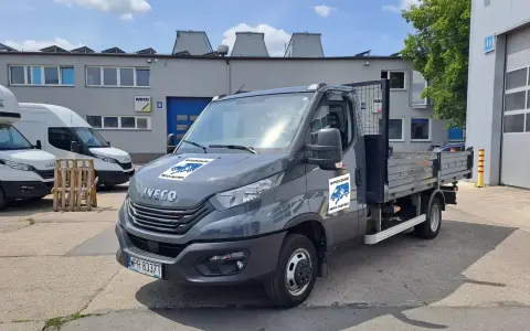 Szary Iveco z otwartą skrzynią ładunkową, idealny do wynajem wywrotki do 3,5 tony. Na drzwiach logo "Wypożyczalnia Moto-Partner".