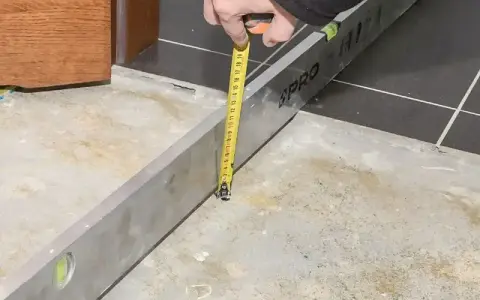 Sprawdzanie, ile schnie wylewka betonowa, za pomocą poziomicy i miarki.