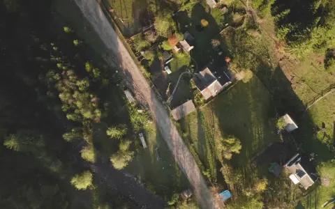 Widok z lotu ptaka na wiejską drogę i domy. Widać, jak pochyła działka wymaga wyrównania, by stworzyć płaski teren pod zabudowę.