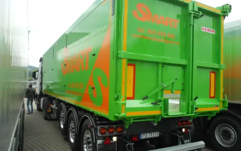 Zielona naczepa wywrotka z pomarańczowym logo SMART. Firma oferuje wynajem naczep wywrotek, tel. 600 456 888.