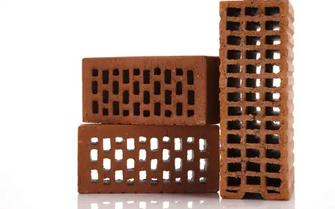 Cegła dziurawka wymiary: trzy cegły ceramiczne z otworami, jedna pionowo, dwie poziomo, na białym tle.