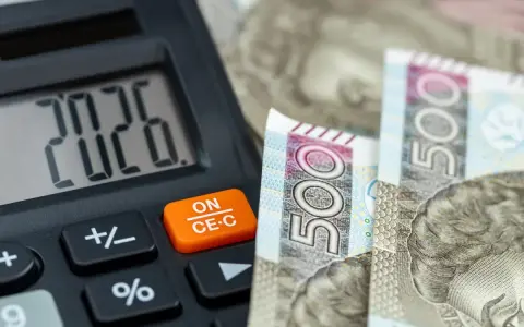 Kalkulator pokazuje 20,26, a obok leżą banknoty 500 zł. To może być odpowiedź na pytanie, ile zarabia pomocnik dekarza na godzinę.