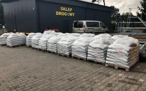 Silosy z materiałem drogowym przed sklepem. Zastanawiasz się, ile kosztuje tona asfaltu? Tu znajdziesz odpowiedź.