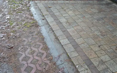 Podbudowa pod kostkę brukową na glinie, z widocznym wzorem ażurowym i kamieniami.