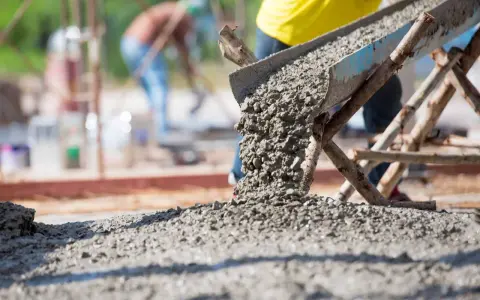 Betoniarka wysypuje świeży beton na plac budowy. Ile betoniarek na 1m3 betonu? To zależy od wielkości betoniarki i jej wydajności.