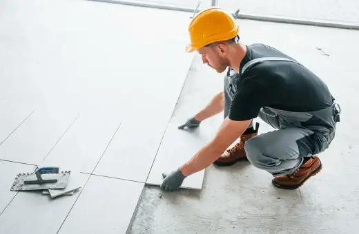 Fachowiec układa płytki na balkonie. Dowiedz się, ile kosztuje położenie płytek na balkonie i jakie materiały są potrzebne.