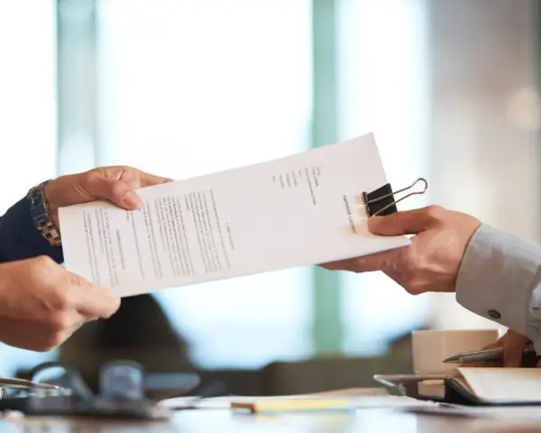 Dwie osoby przekazują sobie dokument "PARTNERSHIP AGREEMENT". To ważny moment, być może ustalanie co to dtr w umowie.