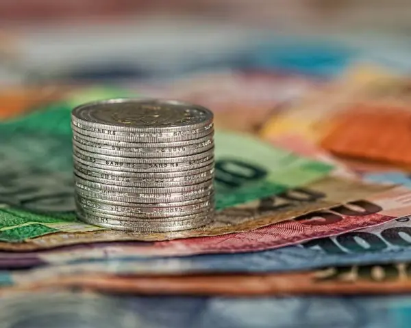 Stos monet na kolorowych banknotach.