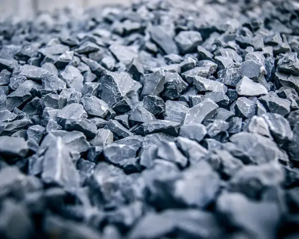 Głęboki, szary żwir do betonu, ułożony w dużą hałdę. Kamienie są ostre i nieregularne, tworząc teksturę idealną do budowy.