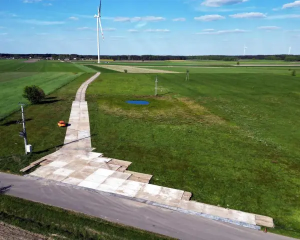 Teren budowy farmy wiatrowej z tymczasową drogą z płyt betonowych. Tłuczeń na drodze ułatwia dojazd ciężkiego sprzętu.